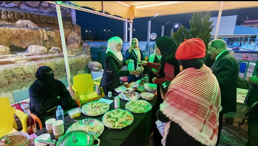 bazar - Center News Network Group of people wearing head coverings around a table of food at an outdoor night event under a yellow canopy.