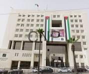 dam - Center News Network Facade of a large white multi-story office building with a wide entrance and a vertical green, white, and red stripe on the facade; cars parked along the street in front.