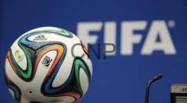 fifa - Center News Network Soccer ball with multicolored panels in front of a blue FIFA backdrop.