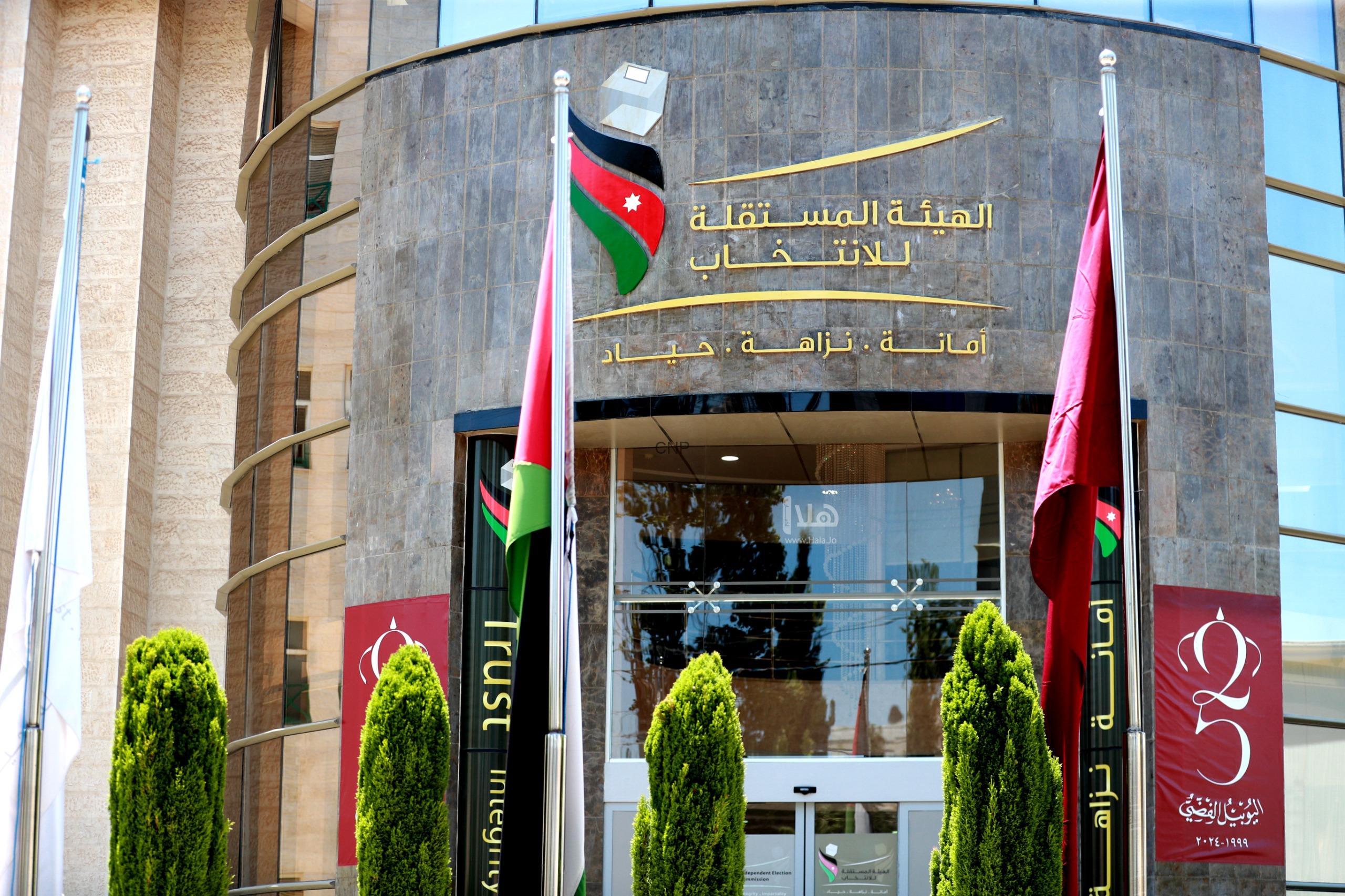 haiaa - Center News Network Front of an Arabic-language government building with gold signage, flags, and green shrubs in the foreground.