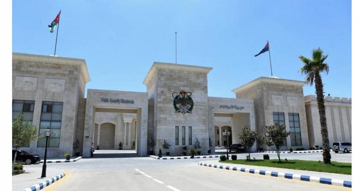 police - Center News Network Front view of a beige stone government-style building with a central crest, three entrance arches, and flagpoles against a clear blue sky; a palm tree on the right and a curved driveway in the foreground.