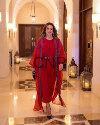ran - Center News Network Woman in a red dress walking toward the camera in a warmly lit hotel hallway with arched ceilings and lanterns along the walls.