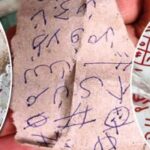 Three torn papers covered in blue and red scribbles, symbols and hash marks, looking like graffiti or cryptic notes photographed up close.