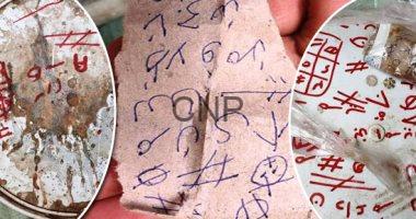 seh - Center News Network Three torn papers covered in blue and red scribbles, symbols and hash marks, looking like graffiti or cryptic notes photographed up close.
