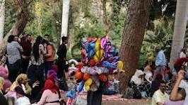 sham - Center News Network Balloon artist wearing a colorful flower headdress performing in a crowded park.