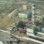 Aerial view of an industrial complex with a tall red-and-white smokestack and multiple buildings.