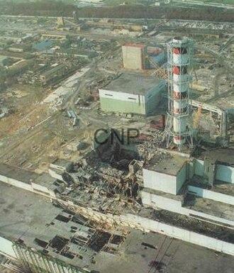 Aerial view of an industrial complex with a tall red-and-white smokestack and multiple buildings.