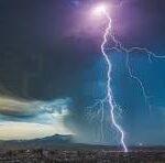 Lightning bolt striking over a flat desert landscape at dusk with a stormy sky; watermark 'CNP' across the center.