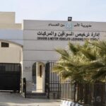 Front view of a government licensing department building with Arabic and English signage, gated entrance, and palm trees nearby.