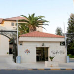 Entrance to a government building with open arches, 'CNP' sign, and Jordan flag waving above on the right side.