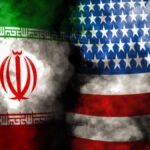Overlapping Iranian and American flags with dark smoke between them, symbolizing tension between the two nations.
