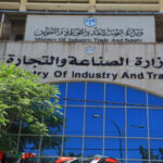 Facade of the Ministry of Industry and Trade building with Arabic and English signs above blue glass windows