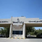 Entrance to Prince Hamzah Hospital with a stone gate and Arabic signage, cars parked in the driveway.