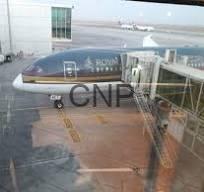 MAD - Center News Network Small private jet parked at a terminal gate, connected to a jet bridge, with water visible beyond the tarmac.