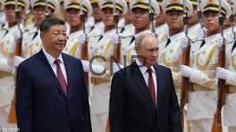 Two men in dark suits walk side by side past a row of ceremonial guards in white uniforms and gold sashes.
