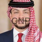 WALI - Center News Network Man wearing a red-and-white checkered ghutra with black agal, navy suit, and red tie in a formal portrait.