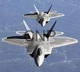 air - Center News Network Two gray military fighter jets fly in close formation over a mountainous landscape, viewed from above.