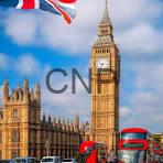 brit - Center News Network Big Ben beside a red double-decker bus on a London street under a blue sky with a Union Jack flag in the background.