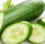 Fresh cucumbers with several slices arranged on a white background.