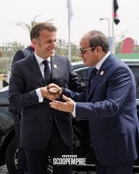 fra - Center News Network Two men in dark suits shake hands in front of a black car at a formal event, with flags in the background.