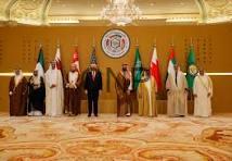 gulf us - Center News Network Group of dignitaries standing in a ceremonial hall with national flags and an emblem backdrop, posing for a formal photo.