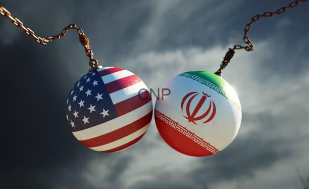 iiiiii - Center News Network Two chained spheres painted with the US flag and the Iranian flag against a cloudy sky, symbolizing US–Iran ties or tension.