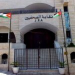 Facade of the Journalists Syndicate building (نقابة الصحفيين) with two Jordanian flags, a metal gate, and steps leading up to the entrance.