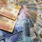 Assorted banknotes from different countries spread out on a surface.