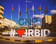 irb - Center News Network Large outdoor city square with a prominent sign featuring a heart symbol and text, flanked by several national flags and modern buildings against a bright blue sky.