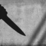 Silhouette of a hand holding a knife raised in the air, cast as a shadow on a textured wall, with the letters CNP centered in the image