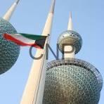 kwit - Center News Network Three Kuwait Towers with a red, white, and green flag waving in the foreground against a clear blue sky.