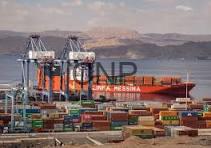 men - Center News Network Port scene with colorful shipping containers and large cranes unloading a cargo ship on a calm sea, in the background left.