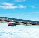 Passenger jet in flight above clouds, dark fuselage with red engine nacelles against a blue sky.