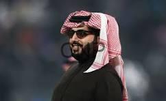 shaaa - Center News Network Portrait of a man wearing a red-and-white keffiyeh and a black thobe, smiling slightly.
