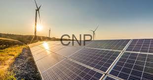 Solar panels in a field with wind turbines on the horizon at sunset, illustrating renewable energy.