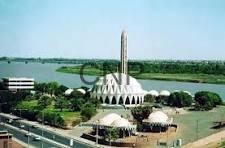 sud - Center News Network White-domed mosque complex with a tall central minaret beside a river and surrounding greenery.