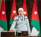 tan - Center News Network Woman at a podium giving an official briefing, with Jordanian flags behind her.