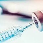 Close-up of a syringe with a needle and vial in soft focus, with the letters CNP overlayed.