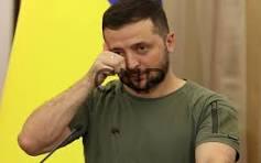 Man in a green t-shirt talking on a mobile phone with a yellow backdrop behind him.