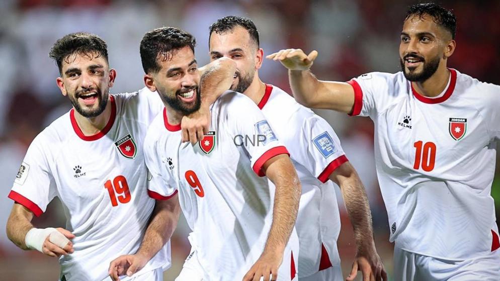 MON - Center News Network Jordanian national football team players celebrate a goal on the field, smiling and embracing each other.