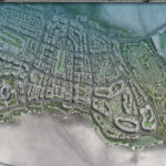 Aerial view of a coastal city with dense streets and a large golf course to the east.
