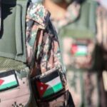 Close-up of two soldiers in camouflage vests with Jordan and Palestinian flag patches, in a desert setting.