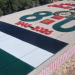 Outdoor memorial slab featuring the Jordan flag, large green numerals, and a red-and-white patterned border on a gravel surface.