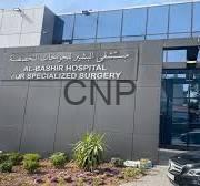 Exterior of a modern hospital entrance with a dark gray sign displaying large 'CNP' letters and smaller text above; glass facade and landscaping nearby.