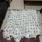 Many small white bags laid out in a grid on a coffee-table-like surface in a living room setting.