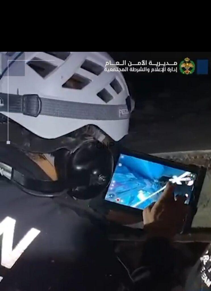 Police officer wearing a protective helmet at night while using a tablet.