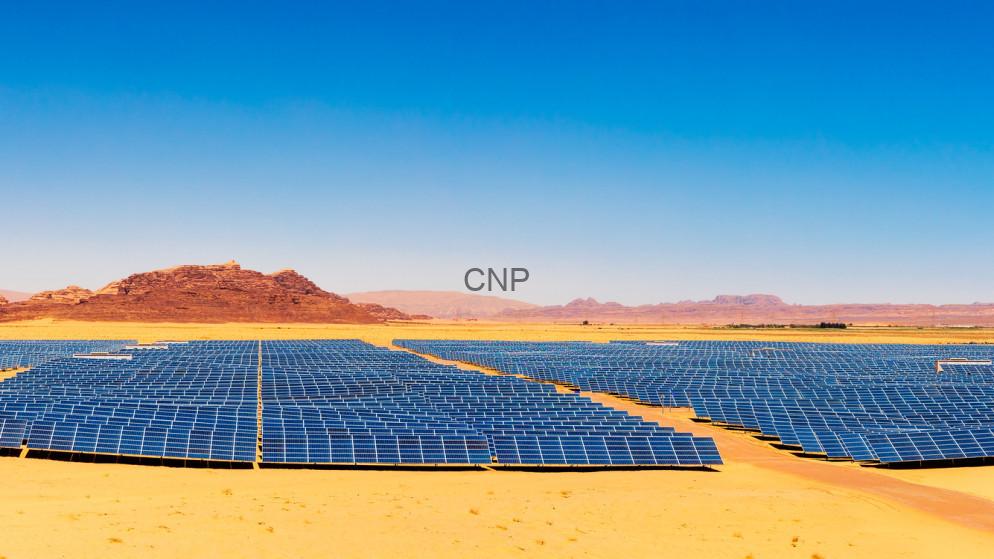 Expansive solar farm with rows of blue solar panels in a desert under a clear blue sky.