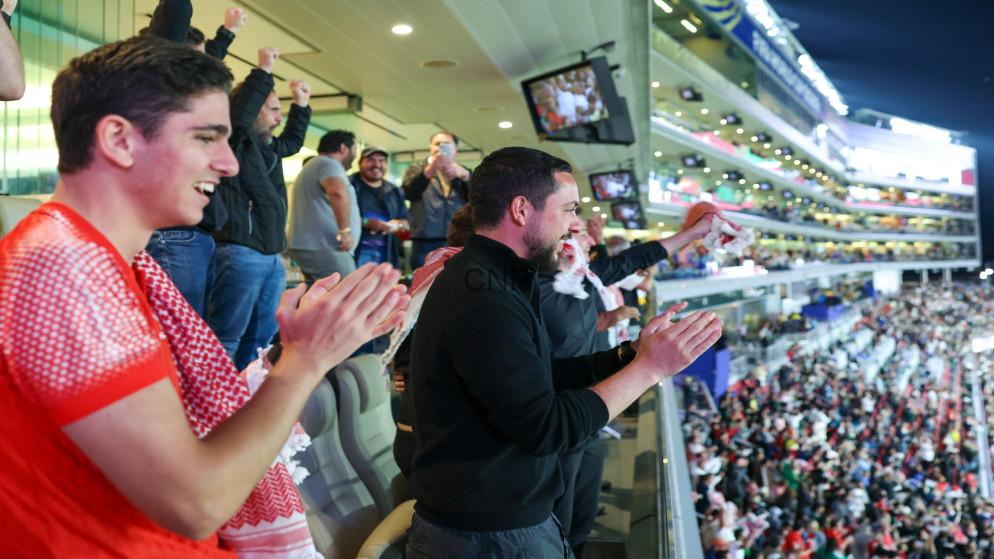 somow - Center News Network Group of spectators standing and clapping in a stadium grandstand during a night game.