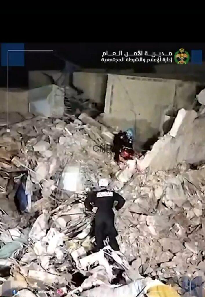 Nighttime rescue scene: responders search through a collapsed building with concrete rubble and debris.