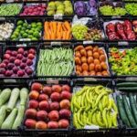 Assorted fresh fruits and vegetables displayed in market crates, organized in colorful rows.